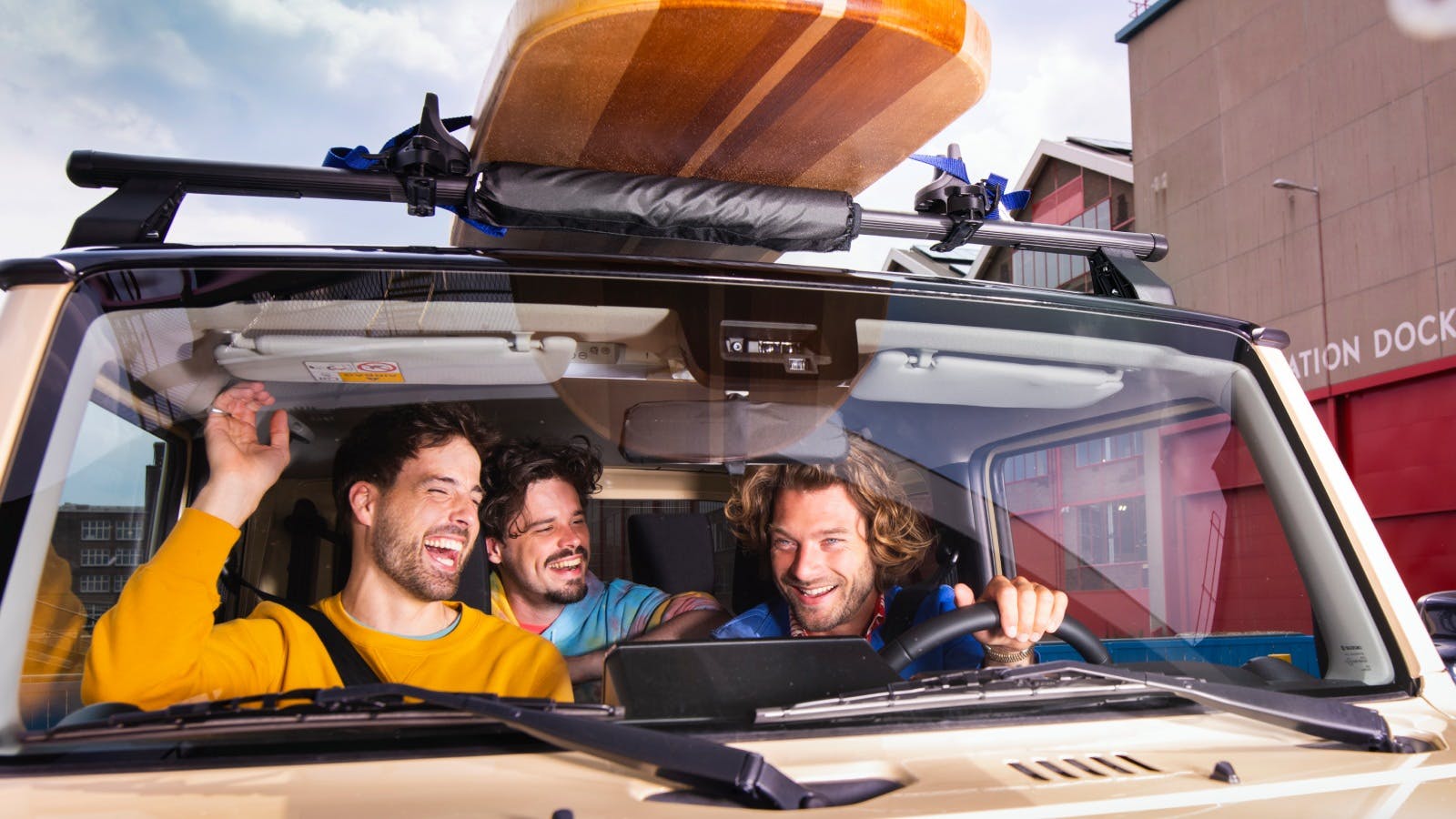 Vrienden lachend in de auto met surfplank op het dak