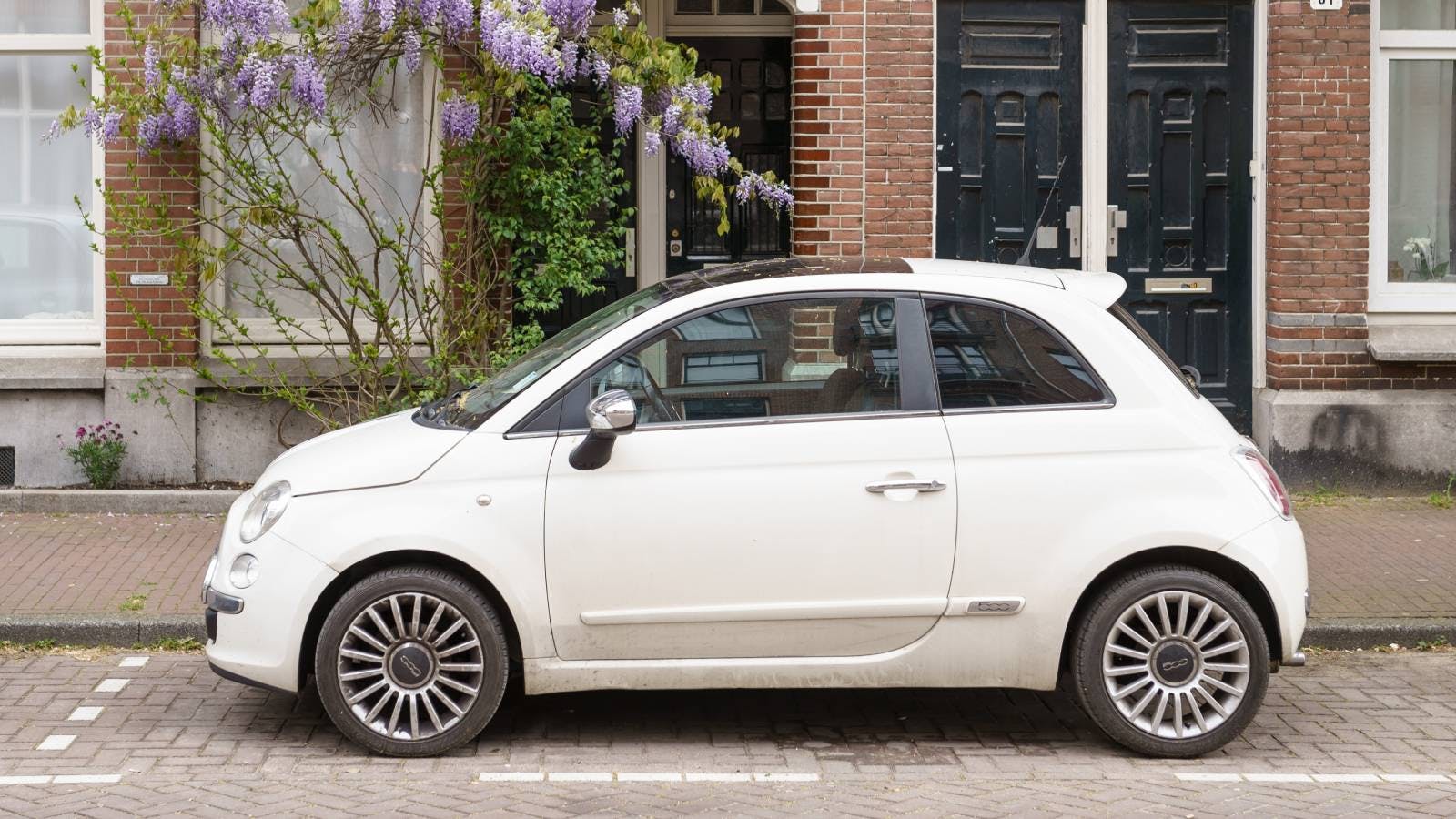 een kleine witte auto staat in een parkeervak