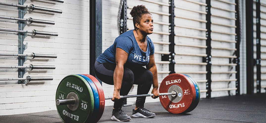 Miloushka tilt met ingespannen frons een halter op met aan elke kant 3 grote gewichten
