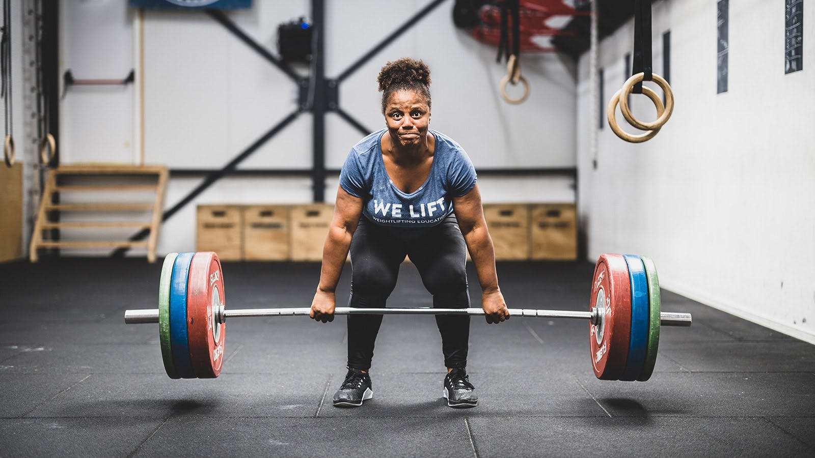 Miloushka tilt met ingespannen frons een halter op met aan elke kant 3 grote gewichten