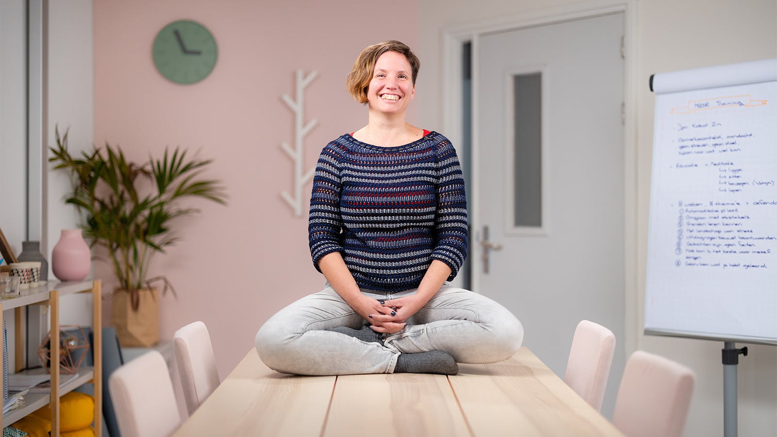 Rienke zit lachend in kleermakershouding op tafel