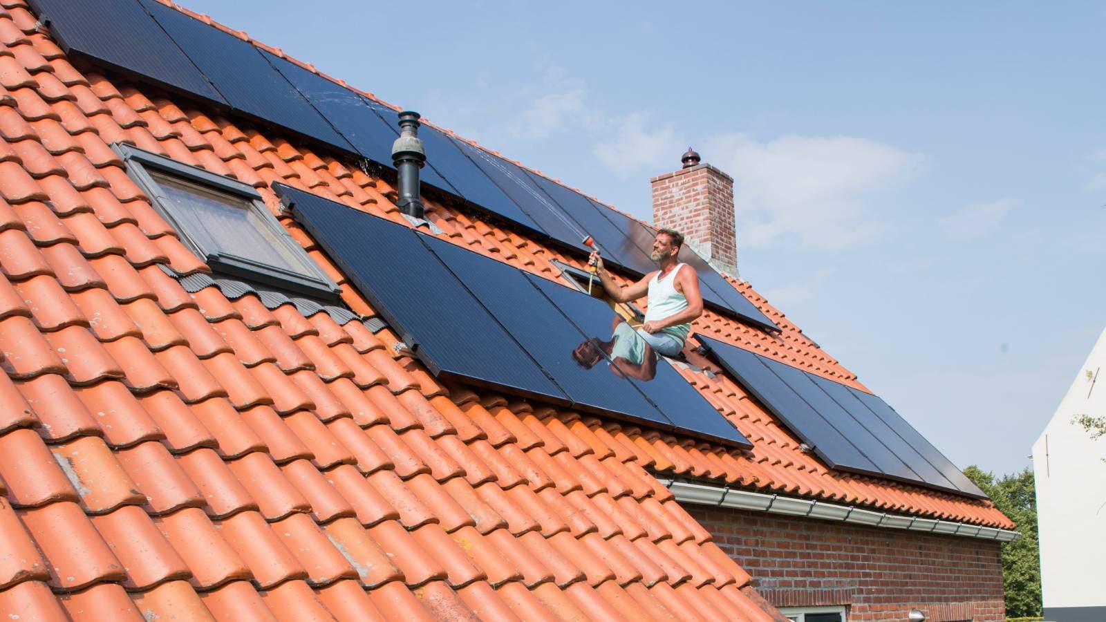 Een meneer installeert zonnepanelen op het dak