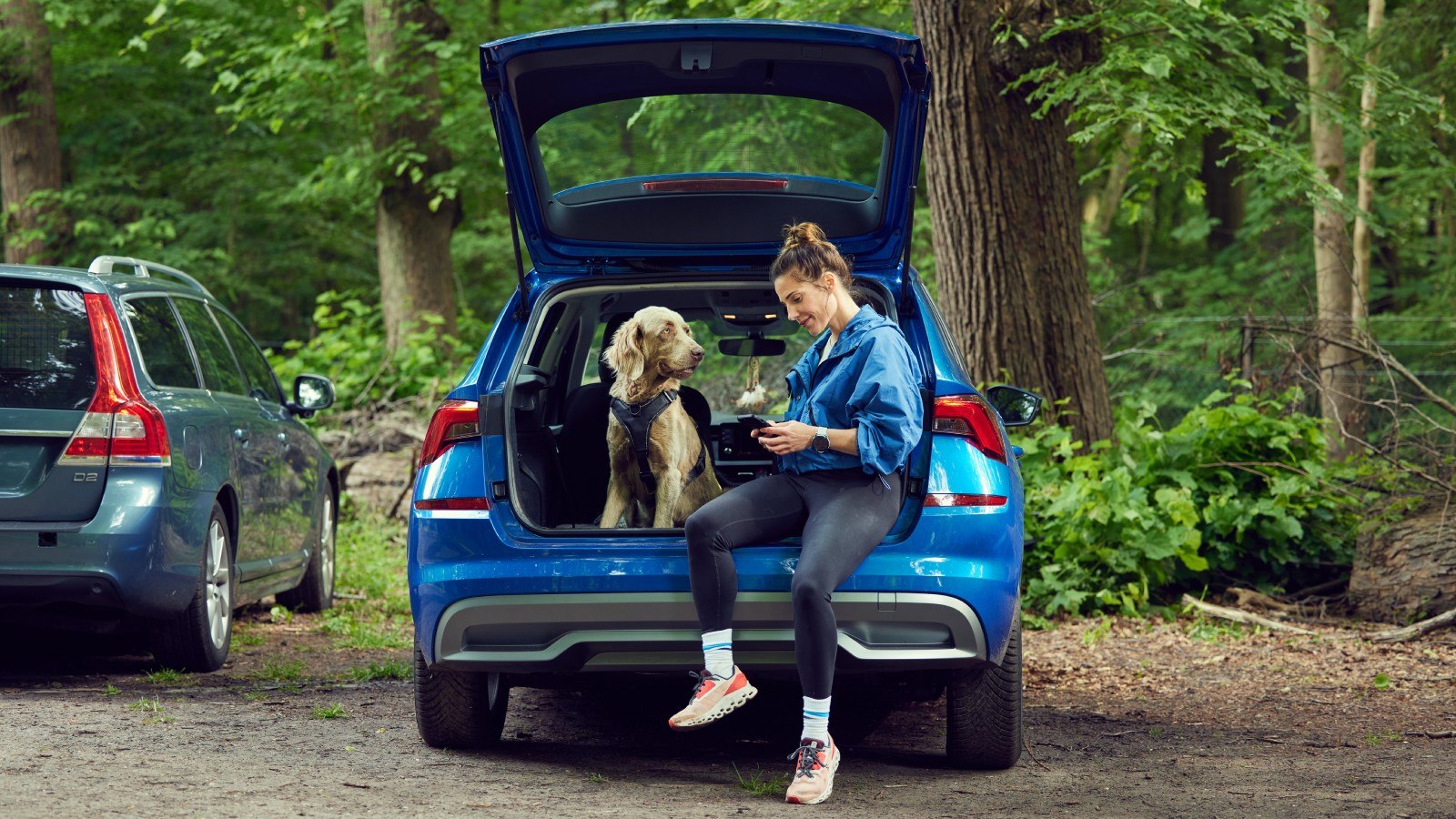 Vrouw en hond zitten in de open kofferbak 
