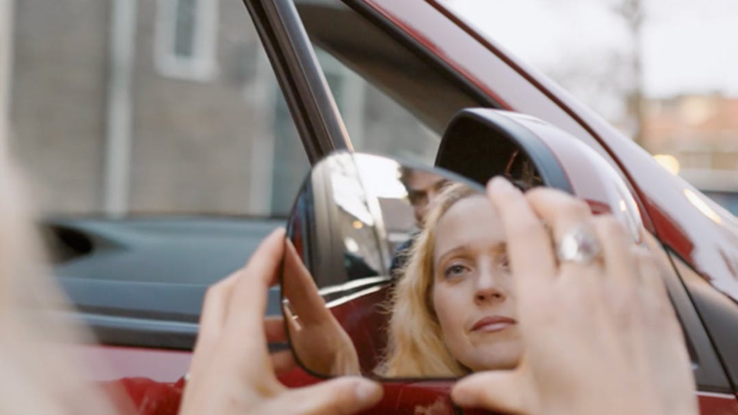 vrouw kijk naar zichzelf in zijspiegel van auto