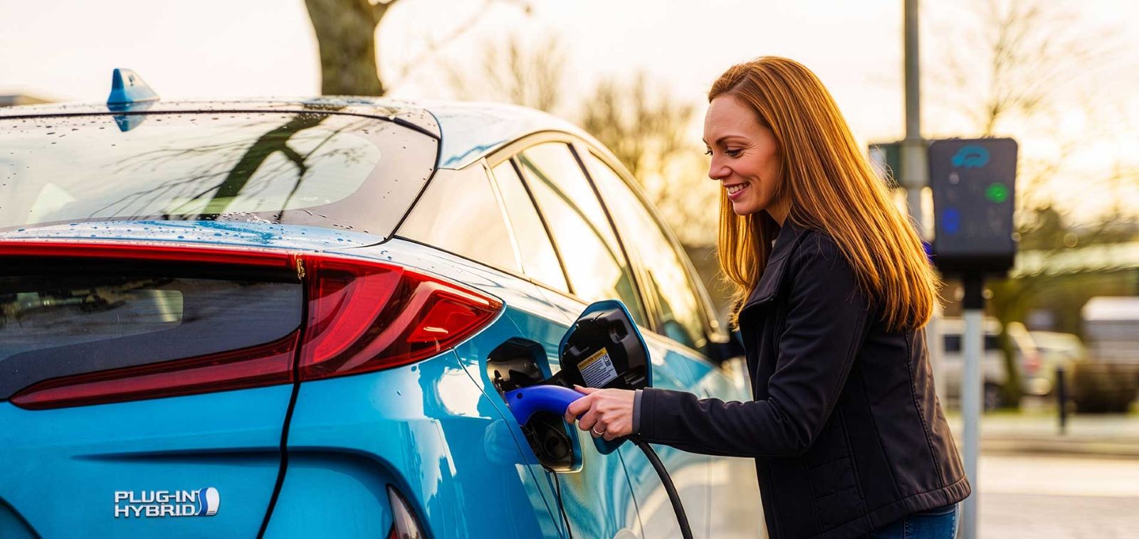 Opladen van een blauwe plug-in hybride auto aan een openbaar laadstation voor elektrisch rijden.