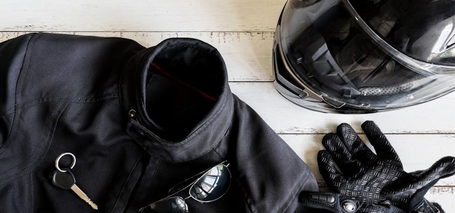 een set van zwarte motorhelm, motorpak, handschoenen, zonnebril en sleutel