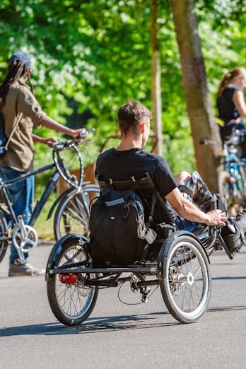 Een invalide man rijdt op zijn handbike tussen andere fietsers