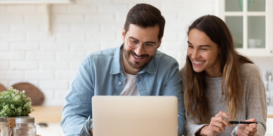 Man en vrouw kijken lachend naar laptop