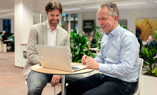 Man in blauwe blouse en jeans wordt geinterview door andere man in grijze colbert en jeans en geeft 3 tips voor  je verzekering tijdens het studeren in het buitenland.