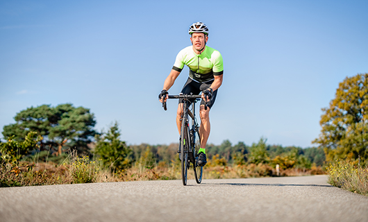 Robert fietst in wielrenners outfit en helm op