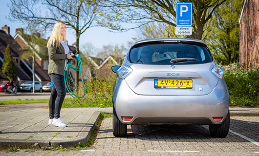 Rowan staat naast haar elektrische auto