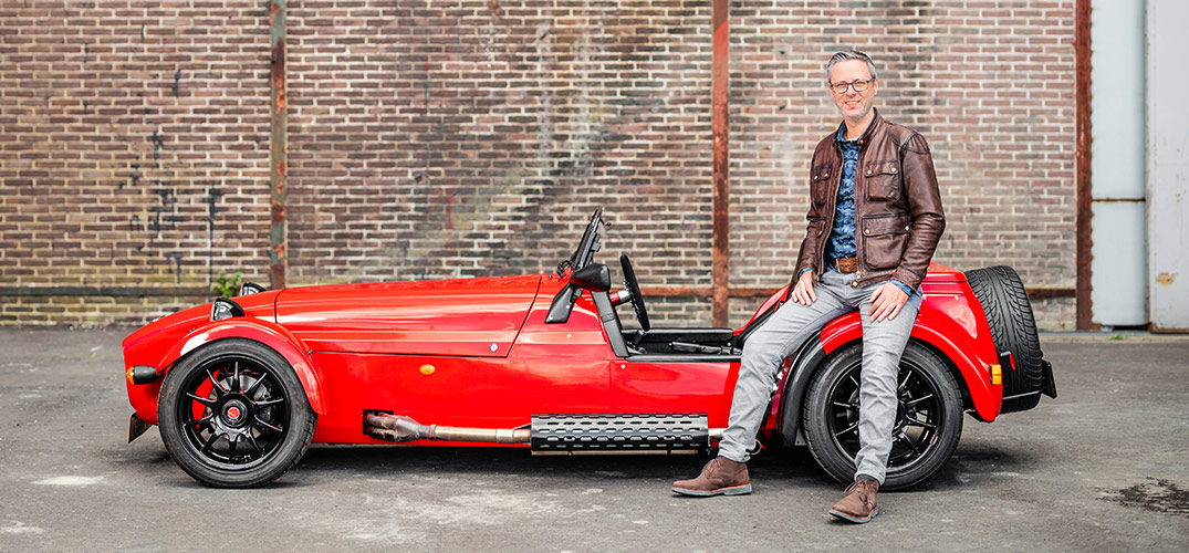 Martijn staat geleund tegen zijn sportwagen