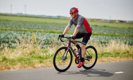 Evert fietst op de racefiets door de weilanden