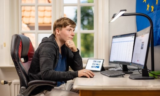 Jorrit zit voor zijn bureau met meerdere beeldschermen