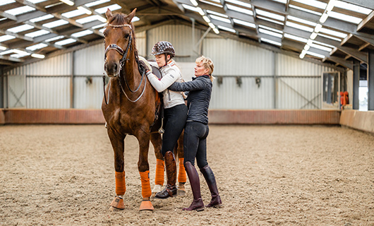 Esra wordt geholpen bij het klimmen op haar paard