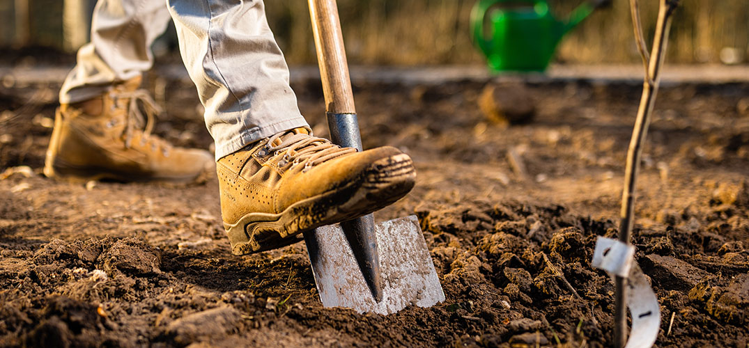 met de voet op de schep de tuin omspitten