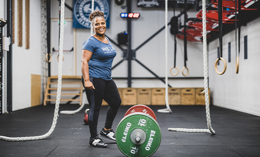 Miloushka staat lachend voor een halter met grote gewichtschijven