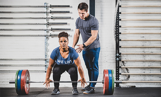 Miloushka wordt bijgestaan door een coach bij het gewichtheffen