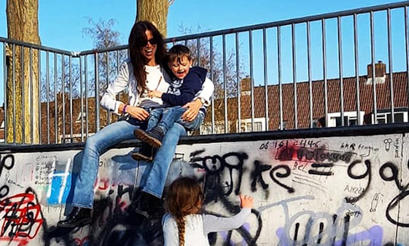 Sanne speelt met haar kinderen bij een muurtje met graffiti
