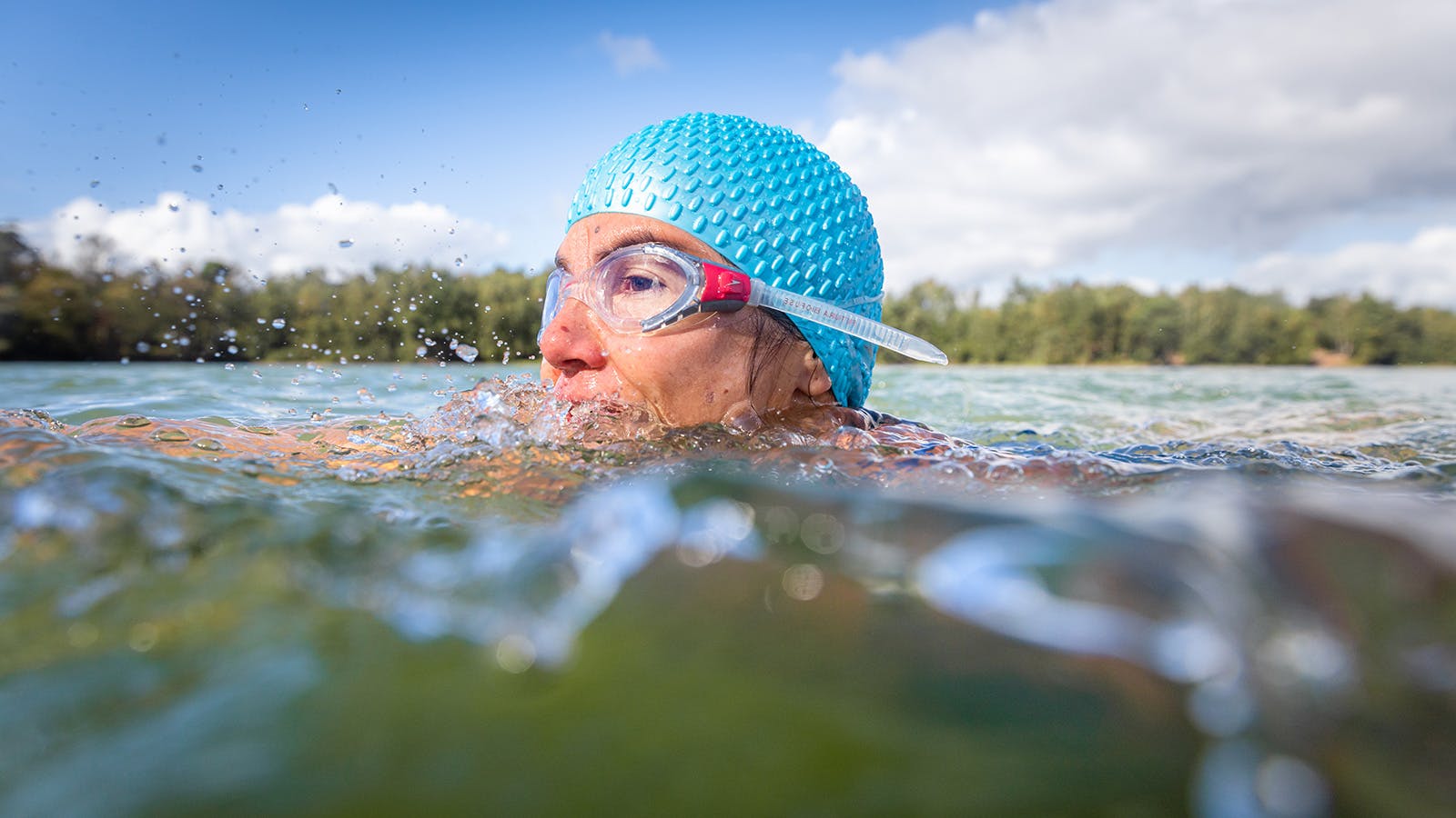 Susan zwemt in open water, haar hoofd met zwembril en badmuts steekt boven water uit