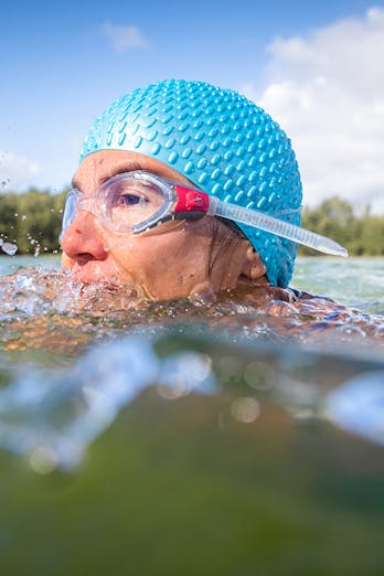 Susan zwemt in open water, haar hoofd met zwembril en badmuts steekt boven water uit