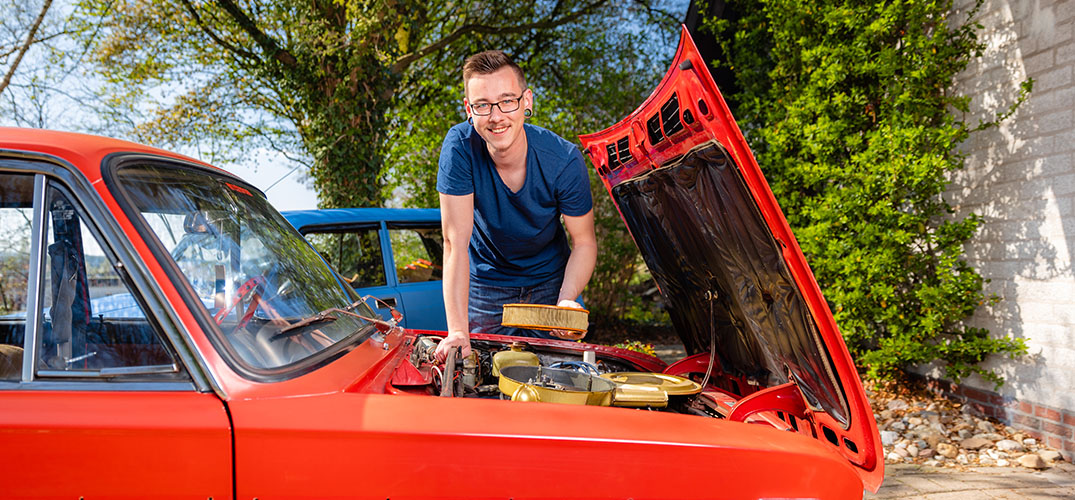 Martijn staat bij de motorkap van zijn rode Lada