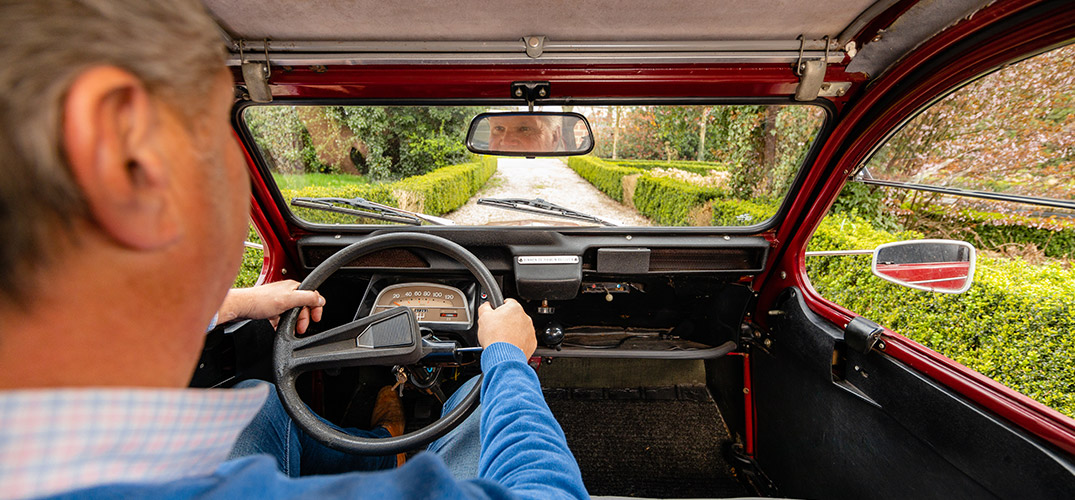Pieter zit achter het stuur van zijn Lelijke Eend