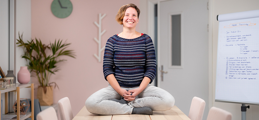 Rienke zit lachend in kleermakershouding op tafel