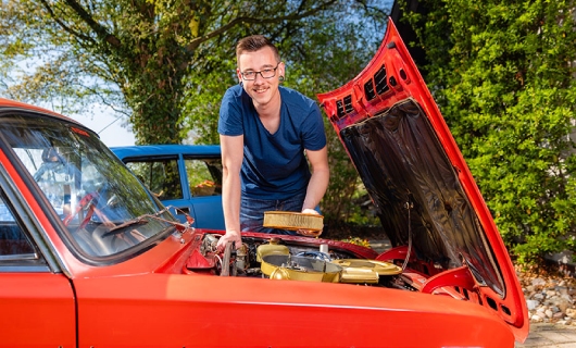 Martijn bij de open motorkap van zijn rode Lada