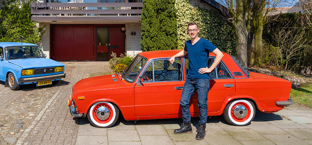 Martijn staat geleund tegen zijn rode Lada