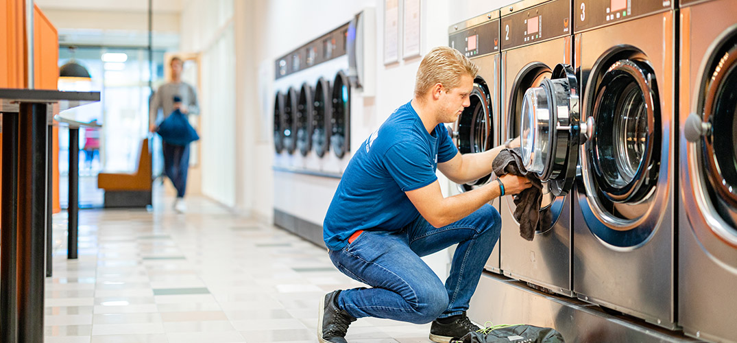 Jens haalt de was uit de wasmachine in de gezamenlijke wasruimte