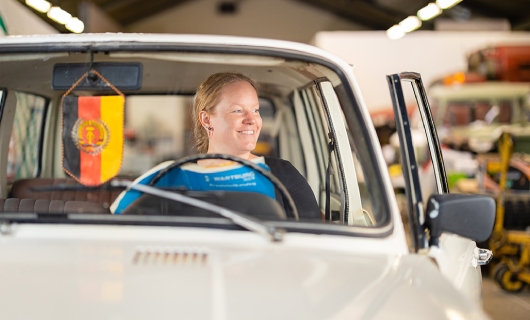Jolien zit in haar oldtimer en kijkt via het zijraam naar buiten
