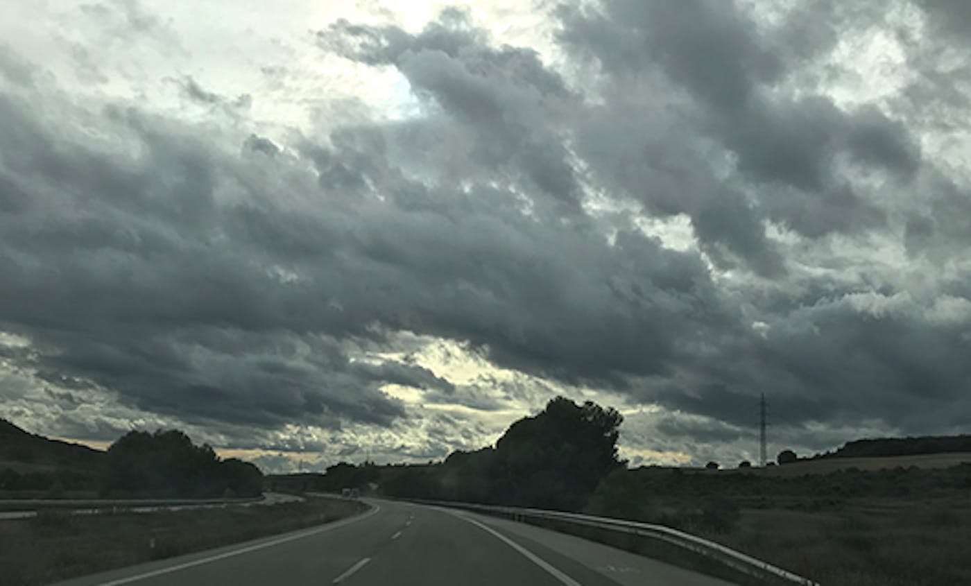samenpakkende wolken boven een weg