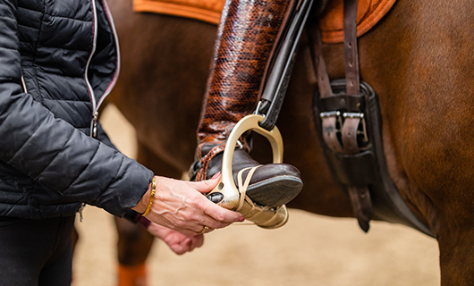 Een rijlaars is vastgebonden aan het stijgbeugel van een paard