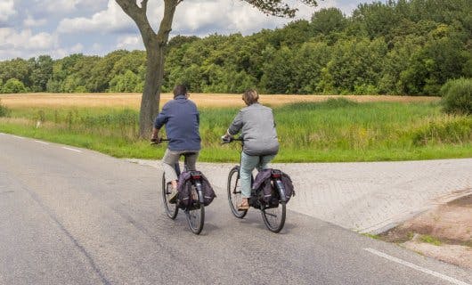 twee mensen fietsen door een groen en weids landschap