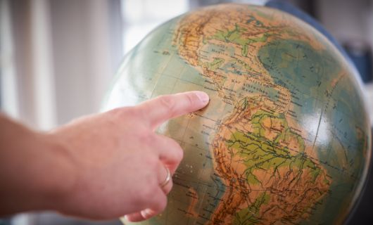 Wijst met vinger plek op wereldbol aan