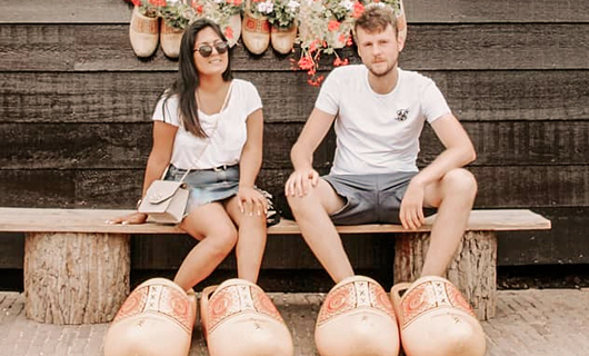 Andrea en Lars zitten op een bankje met enorme Hollandse klompen aan