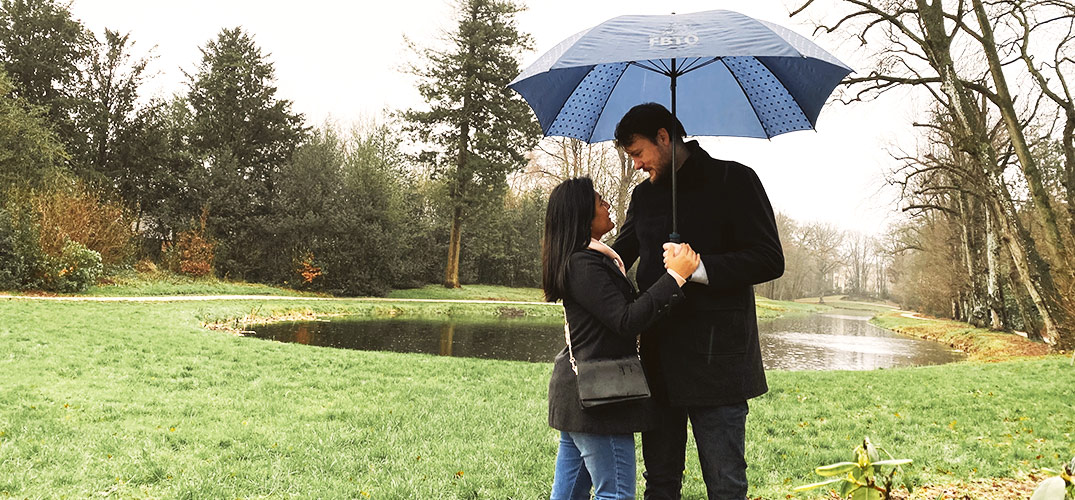 Andrea staat tegen Lars aan, onder de paraplu in een Nederlands parkje