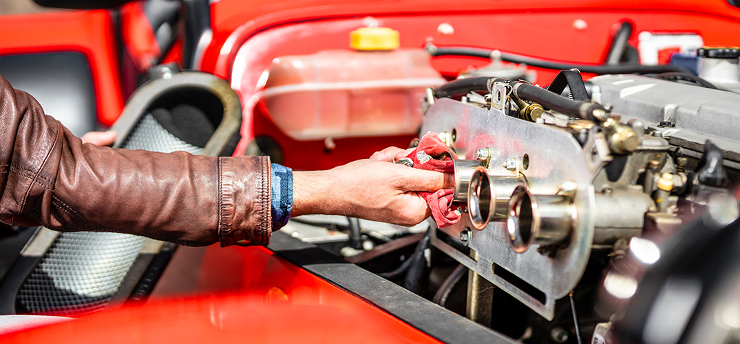 Het uitlaatsysteem van een rode sportauto wordt opgepoetst