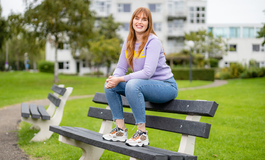 Anouk zit op de rugleuning van een parkbankje