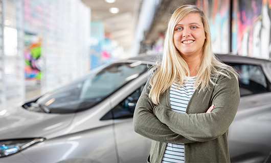 Rowan staat lachend voor haar elektrische auto