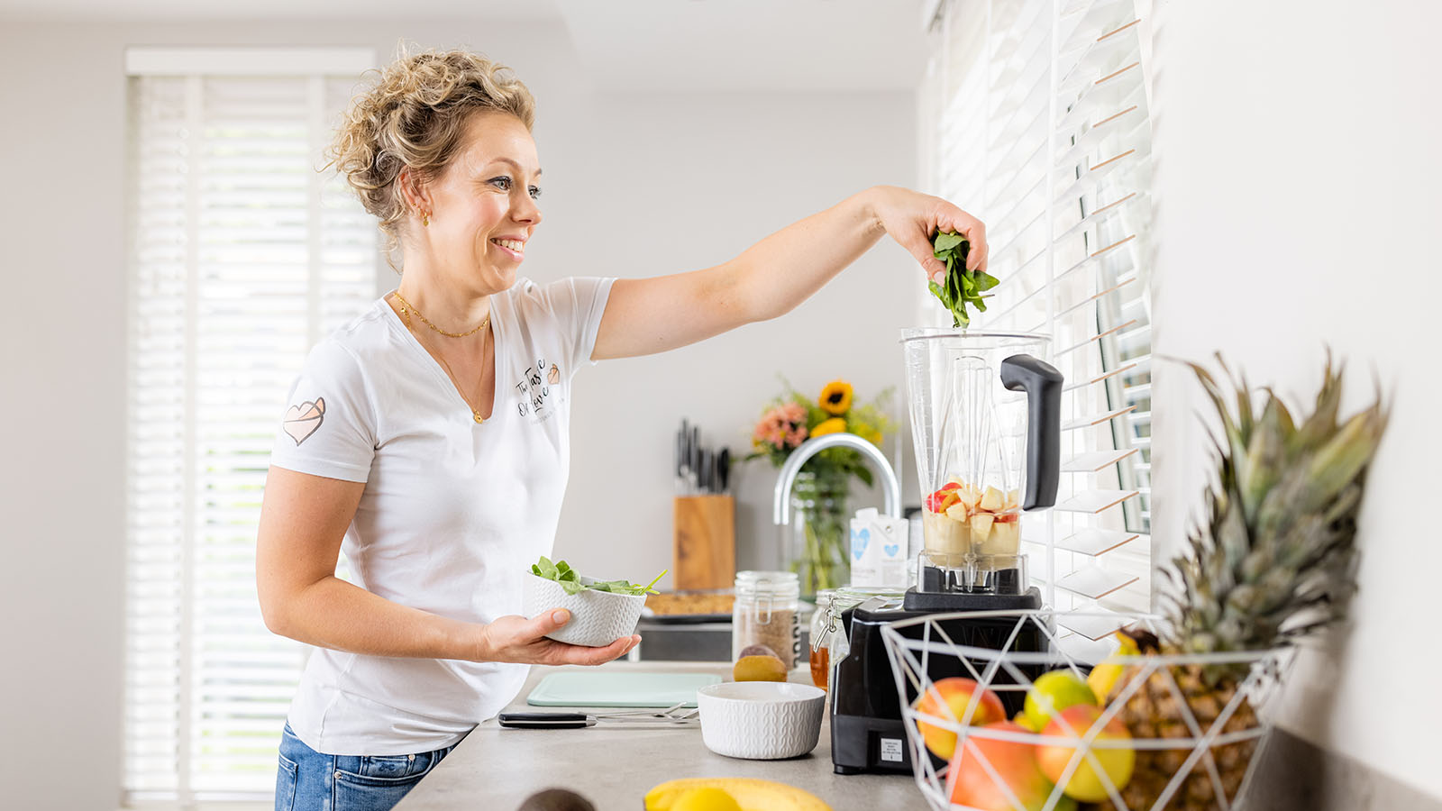 Grietje doet een handvol spinazie in een blender