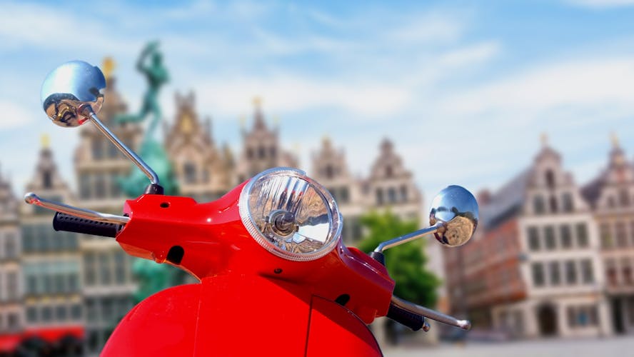 Voorkant van een rode scooter met de gevels van stadshuizen op de achtergrond