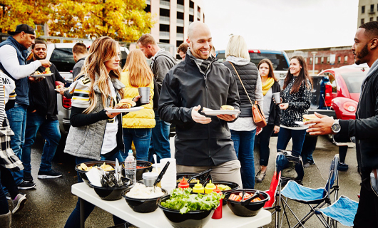 Er lopen veel mensen rond tussen tafels met lekkere hapjes tijdens een buurtfeest