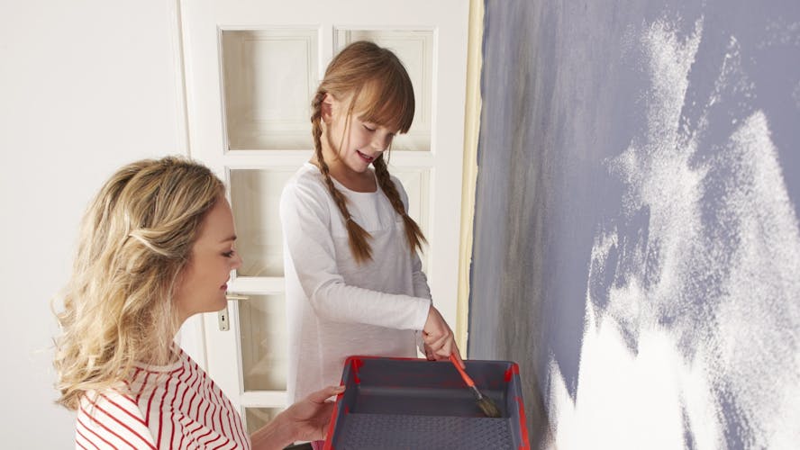 Moeder en dochter beschilderen een witte muur grijs