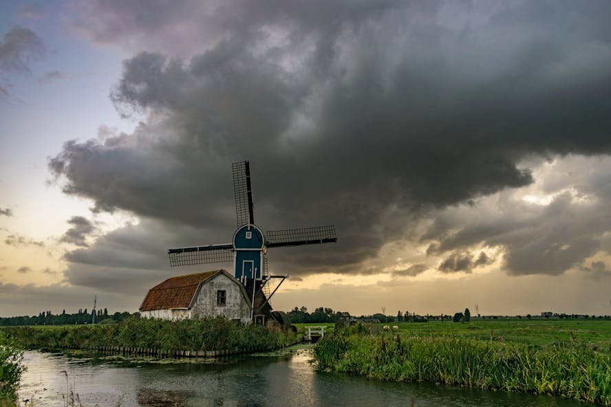 Hollands groen landschap met oude witte schuur en molen, en daarboven samenpakkende donderwolken