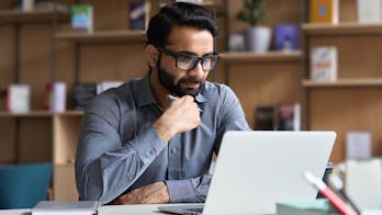 een man zit met zijn computerbril op achter een laptop