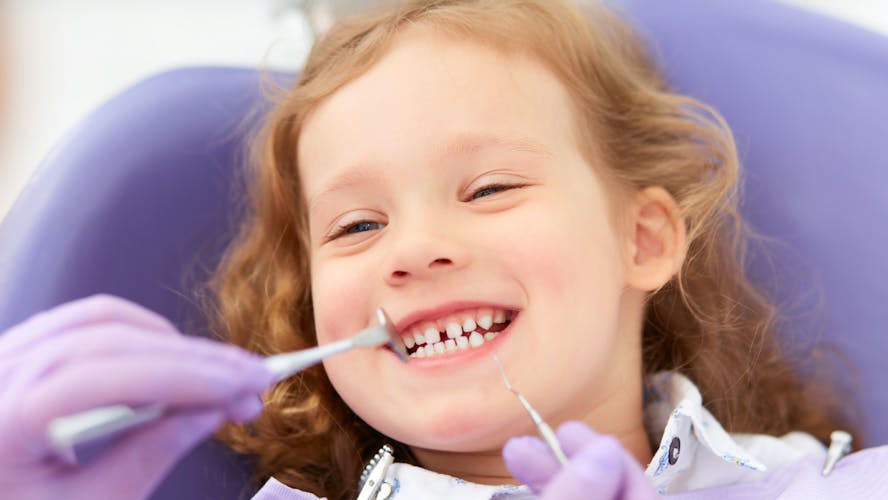 een meisje ligt lachend in de tandartsstoel