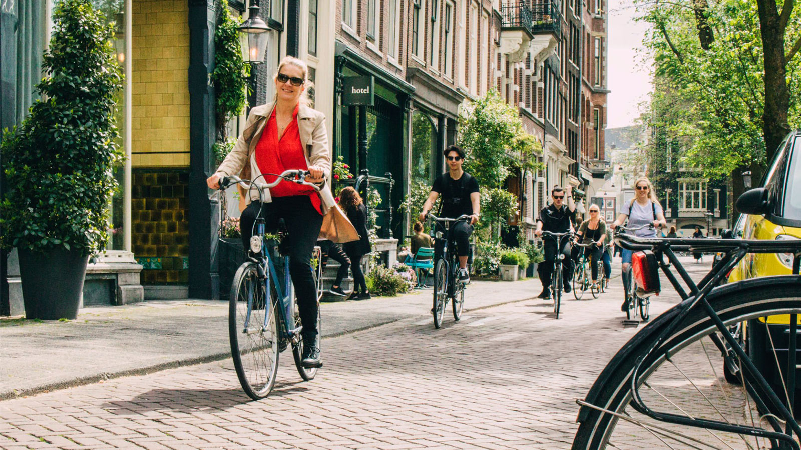 Mensen fietsen op een zonnige dag door een straatje met veel groene beplanting