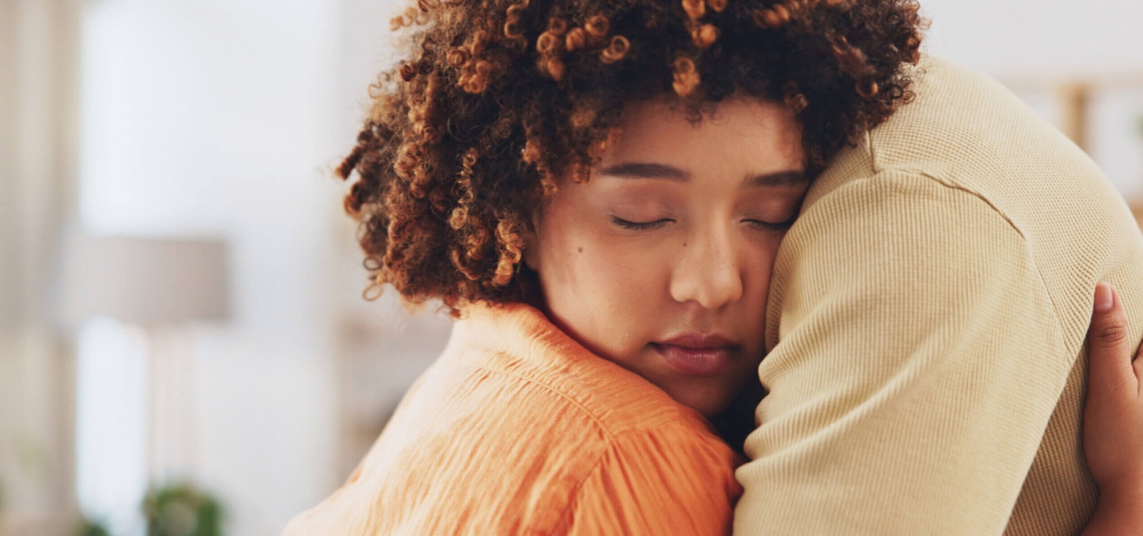 Een meisje met bruin krullend haar geniet slapend van een warme omhelzing die lijkt op die van een verzwaringsdeken.